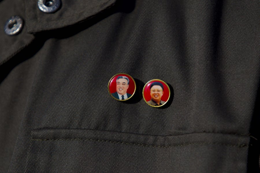 a-north-korean-official-wears-pins-showing-the-late-north-korean-leaders-kim-il-sung-and-kim-jong-il-during-a-tour-of-the-north-koreas-unha-3-rocket.jpg