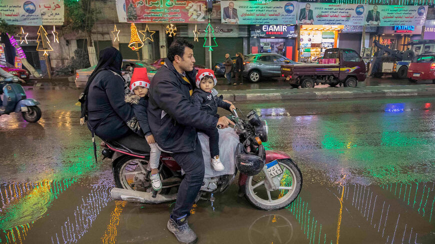 رجل يركب دراجة بخارية مع امرأة وطفلين على طول شارع رئيسي مزين بزخارف عيد الميلاد ورأس السنة الجديدة ، في ضاحية شبرا الشمالية (موطن عدد كبير من المسيحيين) ، القاهرة ، مصر ، 31 ديسمبر 2021.