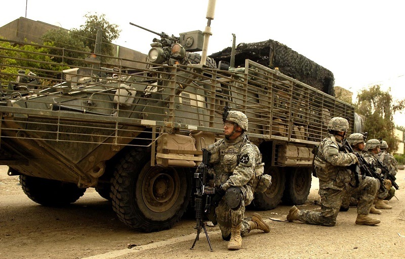 يركع الجنود بجانب مركبة قتالية من طراز سترايكر.