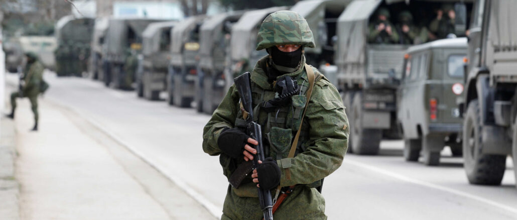 FILE PHOTO: Armed servicemen wait in Russian army vehicles outside a Ukranian border guard post in the Crimean town of Balaclava