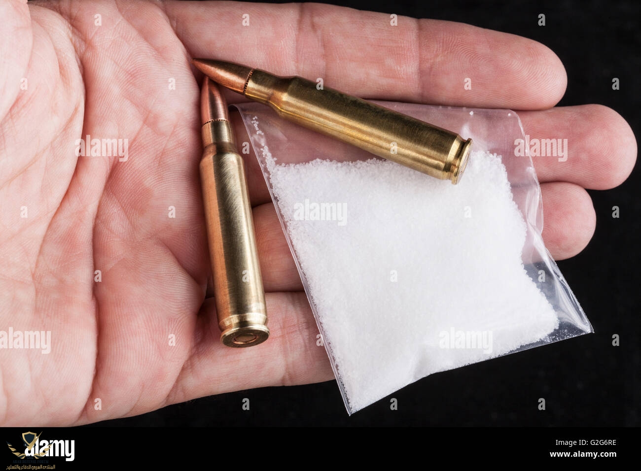 rifle-bullets-close-up-in-hand-on-black-background-with-a-bag-of-white-G2G6RE.jpg