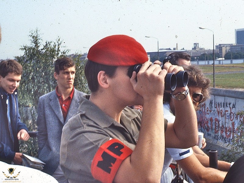 British_military_police_officer_looks_across_Berlin_Wall_with_field_glasses,_1984.jpg