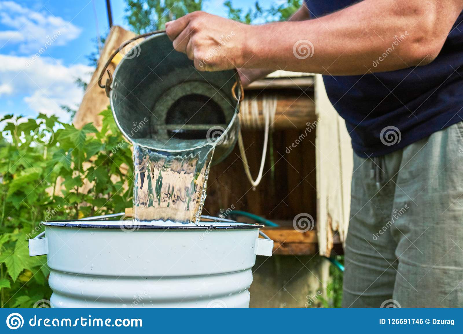 man-pouring-water-just-taken-up-well-enameled-bucket-man-pouring-water-just-taken-up-well-enameled-126691746.jpg