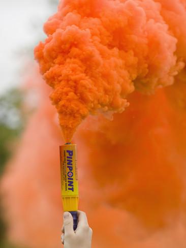 ashley-cooper-hand-holding-an-emergency-flare-with-orange-colored-smoke.jpg