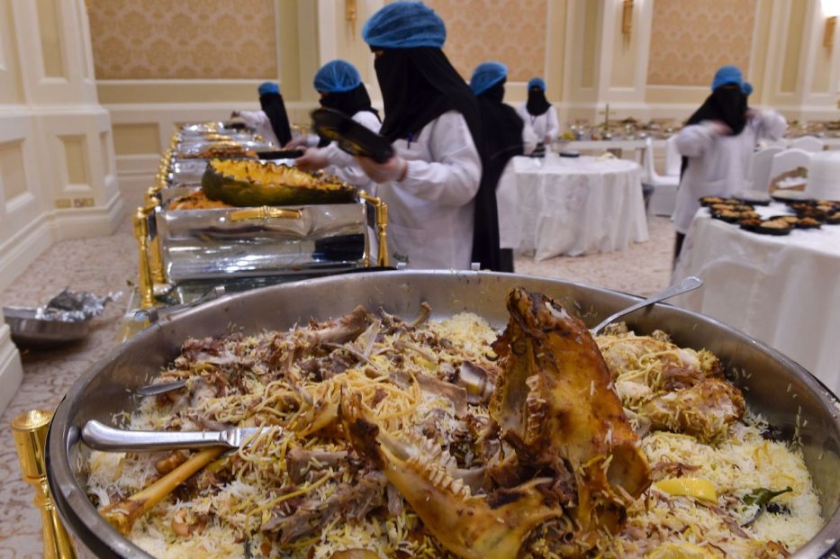 متطوعون سعوديون ، مع بنك الطعام السعودي أو إيتام ، يحزمون بقايا الطعام في صناديق بعد حفل زفاف في الرياض في 3 يوليو / تموز 2019. [FAYEZ NURELDINE / AFP via Getty Images]
