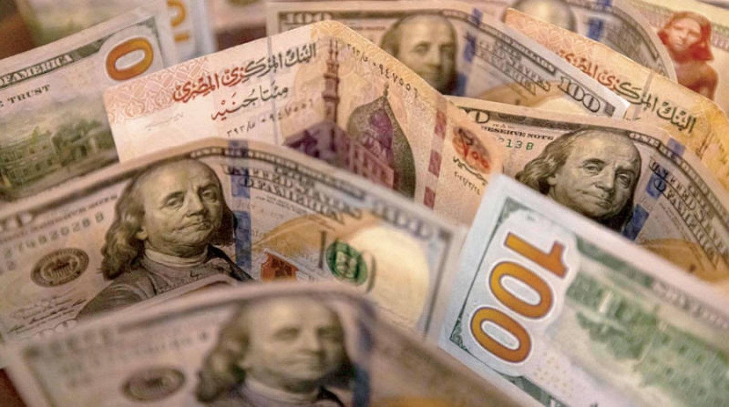 عملات مصرية من فئة 200 جنيه أمام فئات من العملة الأميركية (إ.ب.أ)