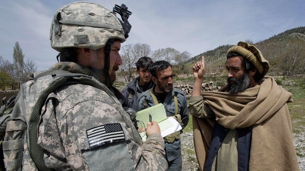 عناصر المخابرات العسكرية الأمريكية يتحدثون إلى ممثل حكومة المقاطعة خلال دورية إعادة الاستطلاع في قرية مير كييل، في شرق أفغانستان في 7 مايو/أيار 2009