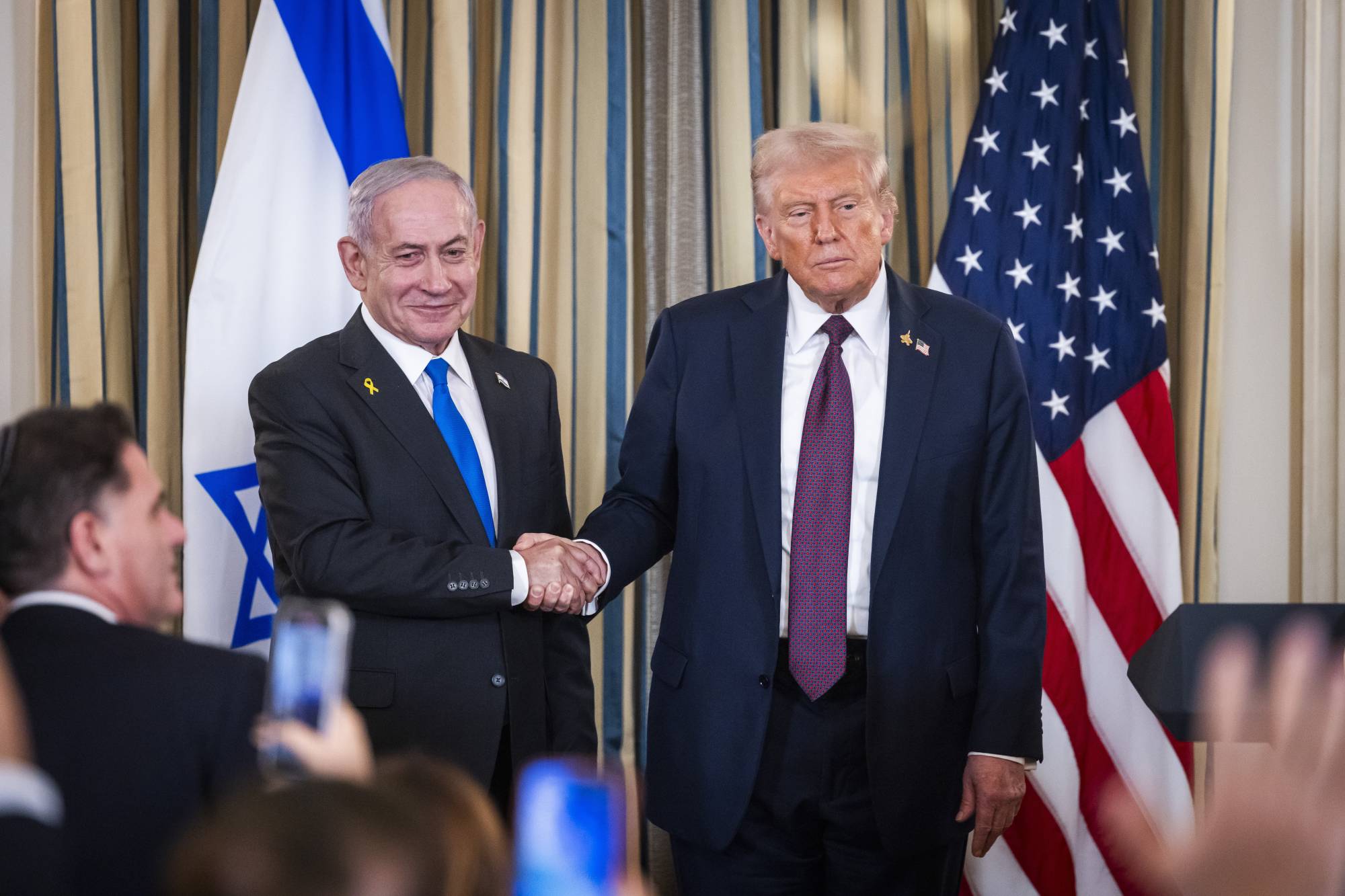 الرئيس الأميركي دونالد ترمب يصافح رئيس الوزراء الإسرائيلي بنيامين نتنياهو في واشنطن (إ.ب.أ)