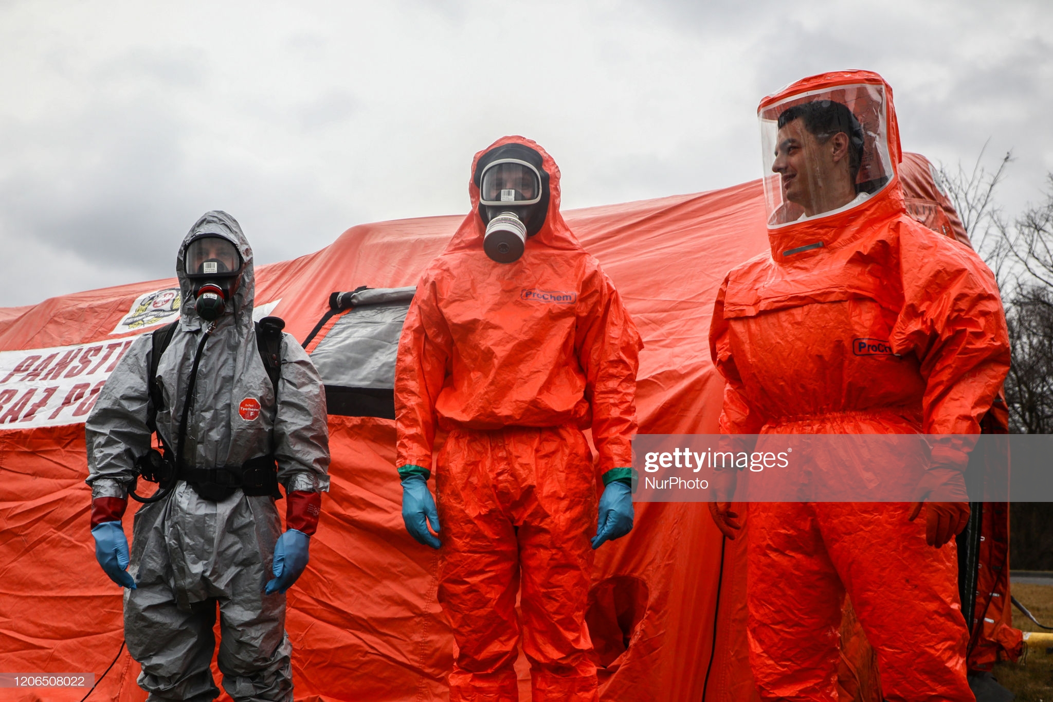 personel-wearing-protective-masks-and-suits-is-pictured-in-front-of-picture-id1206508022