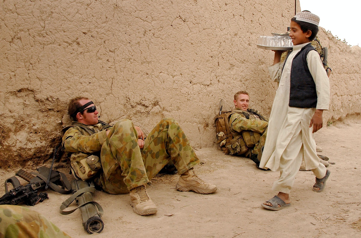 طفل أفغاني يمر أمام جنود من التحالف الدولي في أفغانستان عام 2008 - AFP
