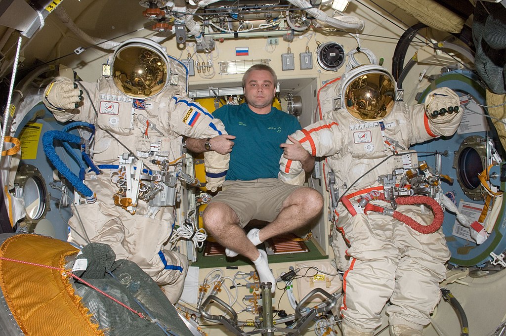 1024px-ISS-22_Maxim_Suraev_with_two_Russian_Orlan-MK_spacesuits_in_the_Poisk_module.jpg